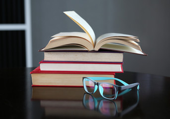 Open book, hardcover books and glasses on wooden table. Education background.