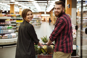 Smiling loving couple in supermarket with shopping trolley