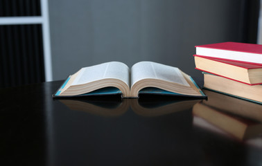 Open book and hardcover books on wooden table in library. Education background.