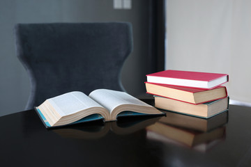 Open book and hardcover books on wooden table in library. Education background.