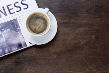 Close-up top view of coffee cup and newspaper on wooden table