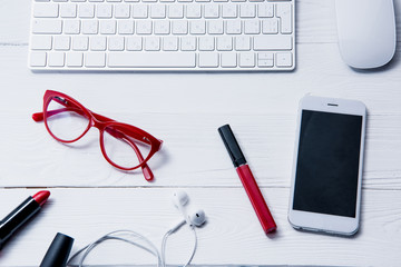 top view of smartphone, keyboard and beauty supplies on table