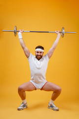 Fototapeta na wymiar Full length of athletic man doing squatting exercises with barbell