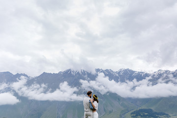 young couple in love, cuddling, a man in a suit and girl in white with flowers