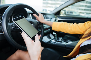 Naklejka premium Zamknij się obraz z żeńskim kierowcą i pustym ekranem telefonu