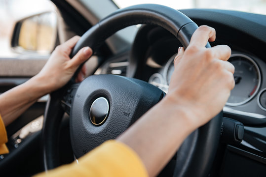 Female hands on steering wheel while driving a car
