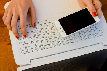 Closeup on woman working using mobile phone and computer. Top view mock up screen and wooden table background