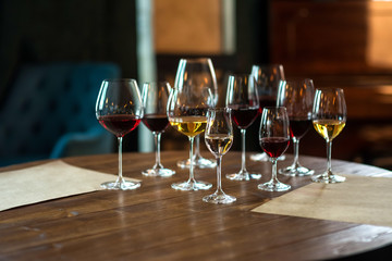 Collection of wine glasses with different wine on wooden table in restaurant. Life style