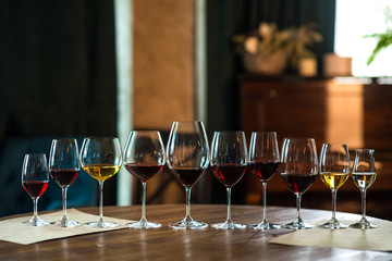 Glasses of red and white wine in a cozy room on wooden table, vintage color with text space