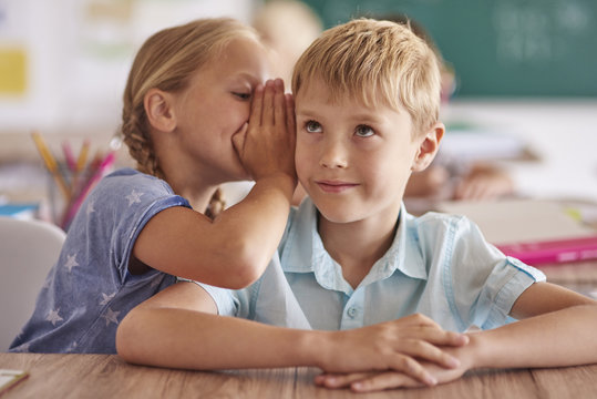 Boy and girl whispering in classroom