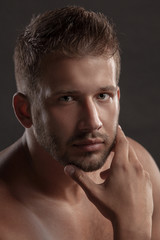 Model man with an open  chested on a dark background , muscular body of a young man in jeans . Shot in a studio .