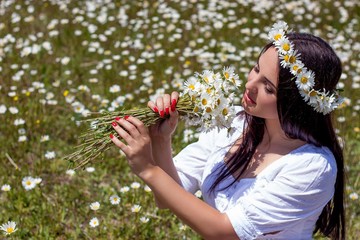 Portrait of a beautiful young woman in chamomile field. Happy girl collecting daisies. A girl resting in a field of chamomile. S