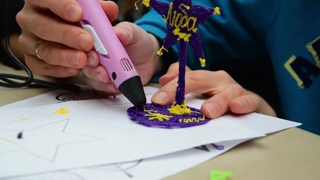 Woman teaches child to use a 3D pen
