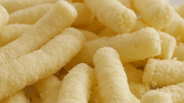 Corn flips puffs unhealthy food pile close-up slow tilt 4K 2160p 30fps UltraHD footage - Puffcorn snack in the bowl shallow DOF 3840X2160 UHD tilting video 