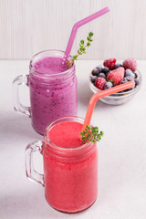 Summer berries smoothie in the jars on white rustic background