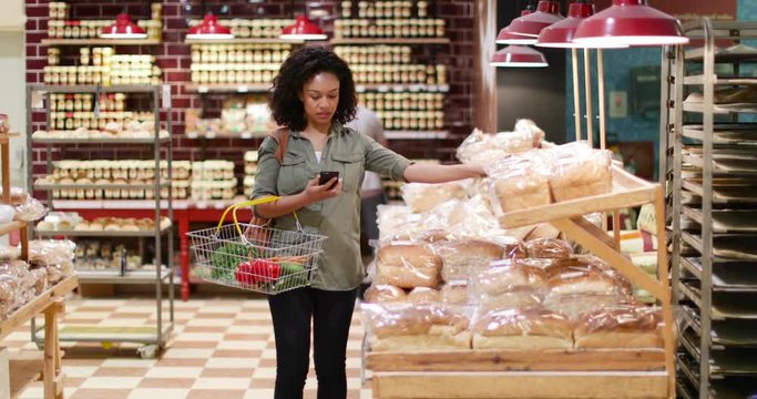 Woman grocery shopping and using smartphone