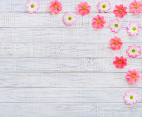 Spring flowers frame with pink daisy flowers over wooden background