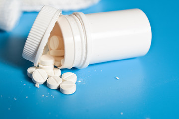 A bottle with pills on a blue background. Place for your text