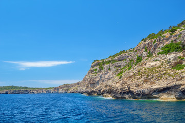 Menorca island coast with the cliffs covered with green bushes.
