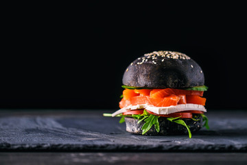 Delicious burgers of black dough with red fish on a beautiful slate board