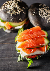 Delicious burgers of black dough with red fish on a beautiful slate board