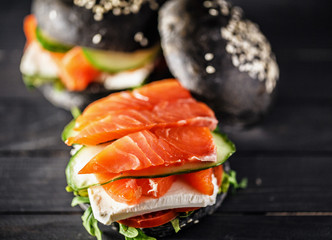 Delicious burgers of black dough with red fish on a beautiful slate board