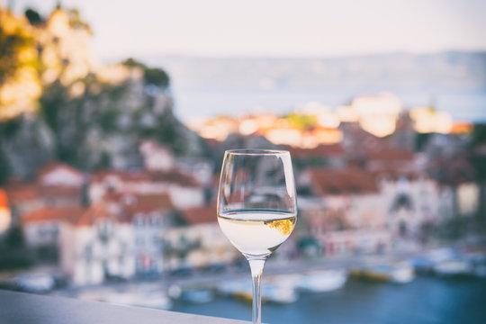 Glass of wine with Omis Riviera view, relax seascape background in soft sunset light, Dalmatia, Croatia