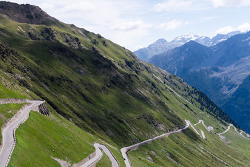 Fototapeta na wymiar Alp road surrounded by blue alp high mountains. Steep descent of Passo dello Stelvio in Stelvio Natural Park, Tyrol, Italy.
