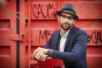 Blue jacket guy against red container, smiling