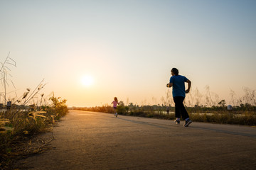Fototapeta na wymiar silhouette woman running on road at sunset background