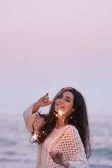Fototapeta na wymiar Woman with sparklers near the sea