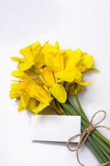 Daffodil bouquet tied with rope and greeting card on a white background, top view