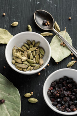 Cardamon seeds, barberry and other condiments on a black wooden table, top view. Ingredients composition, flat lay, vertical