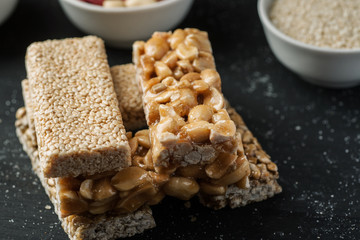 Sesame and peanuts bars stacked on a black wooden table closeup shot