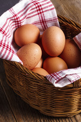 Chicken eggs in a willow basket with a kitchen towel