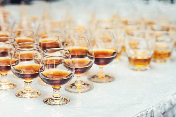 Row of glasses with whiskey or cognac on the table. Strong alcohol in a bar or restaurant.