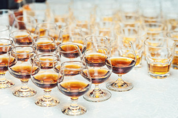 Row of glasses with whiskey or cognac on the table. Strong alcohol in a bar or restaurant.
