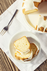 Slices of glazed easter cake and sliver fork on a white linen cloth, top view