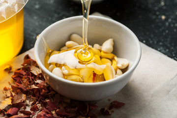 Raw peanuts in a white ceramic bowl poured with thick honey trickle