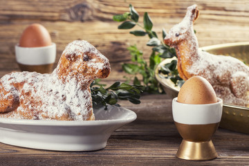 Eggs in a cups, lamb and rabbit easter cake on a wooden table