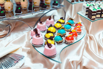 blue yellow red pink sweets on a glass stand on the wedding candybar