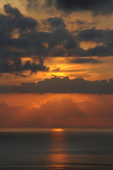 Breathtaking sunset over the Atlantic Ocean with thin clouds like molten lava, monochromatic vies with dark grey and golden yellow hues of the sunlight and clouds, in Tenerife, Canary Islands, Spain 