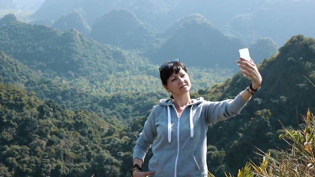 Smiling woman making selfie at the mountains background. Full HD slow motion stock footage.

