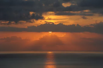 Fotobehang Atmospheric sunset over the Atlantic Ocean with thin clouds like molten lava, monochromatic vies with dark grey and golden yellow hues of the sunlight and clouds, in Tenerife, Canary Islands, Spain  © Ana