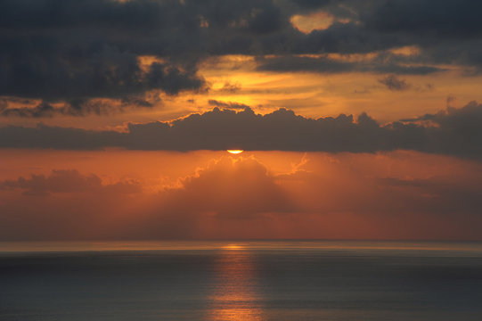 Atmospheric sunset over the Atlantic Ocean with thin clouds like molten lava, monochromatic vies with dark grey and golden yellow hues of the sunlight and clouds, in Tenerife, Canary Islands, Spain 
