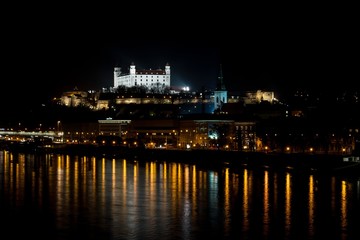 Fototapeta premium Bratislava, Slovakia - March 19, 2017: Night view of Bratislava castle and Danune river in capital city of Slovakia with its reflection