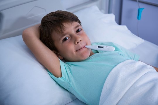Patient lying on bed with thermometer in hospital