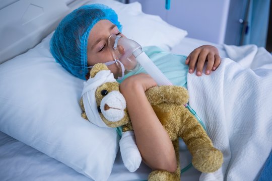 Patient with oxygen mask relaxing on bed in ward