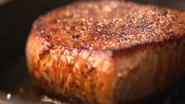Delicious healthy hearty meal close-up. We cook meat in the kitchen in a frying pan. red steak cooking on skillet garnished with salt and pepper. Rapid