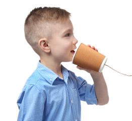 Cute little boy using plastic cup as telephone, on white background